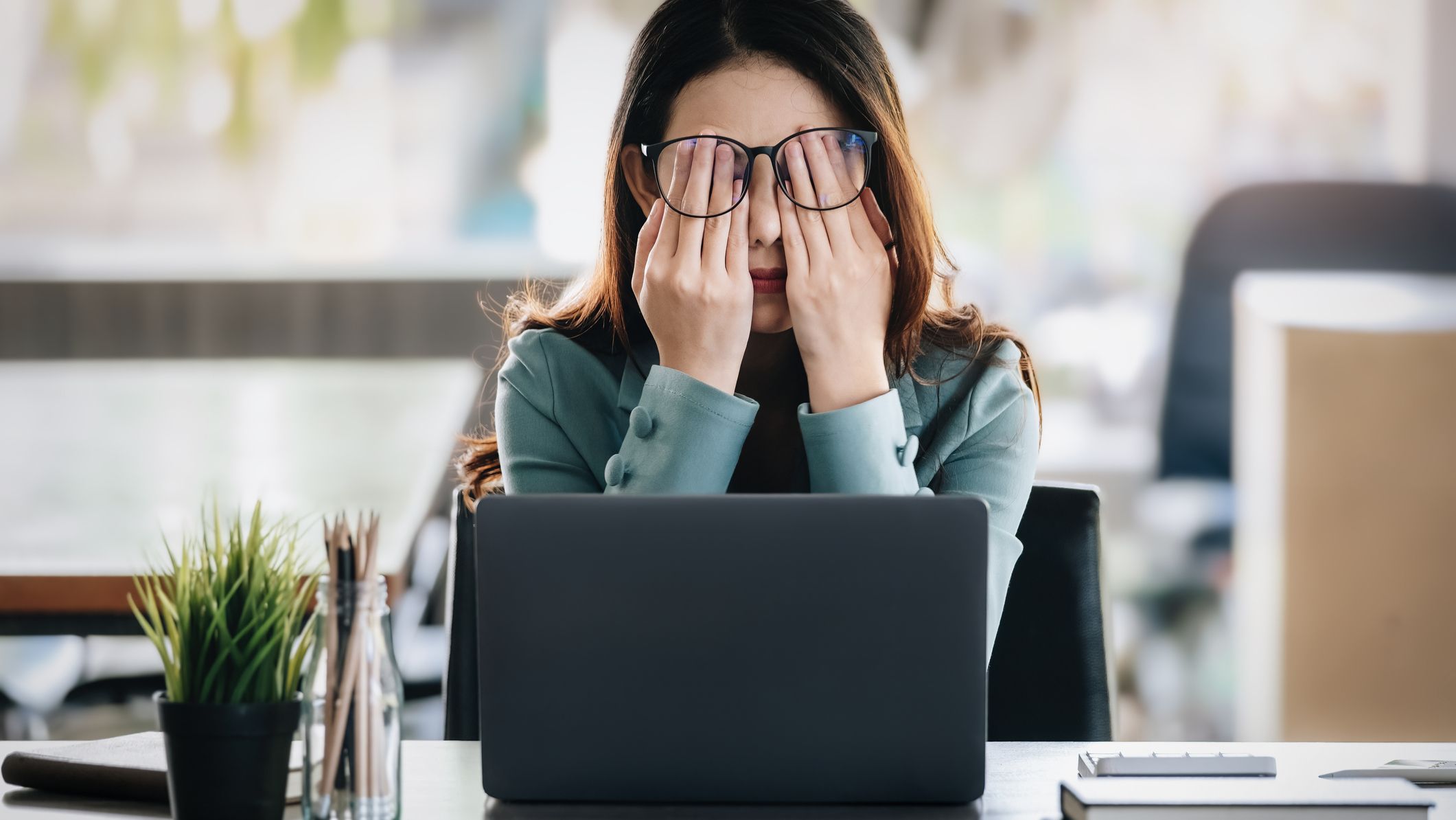 woman in front of laptop expressing frustration and fatigue